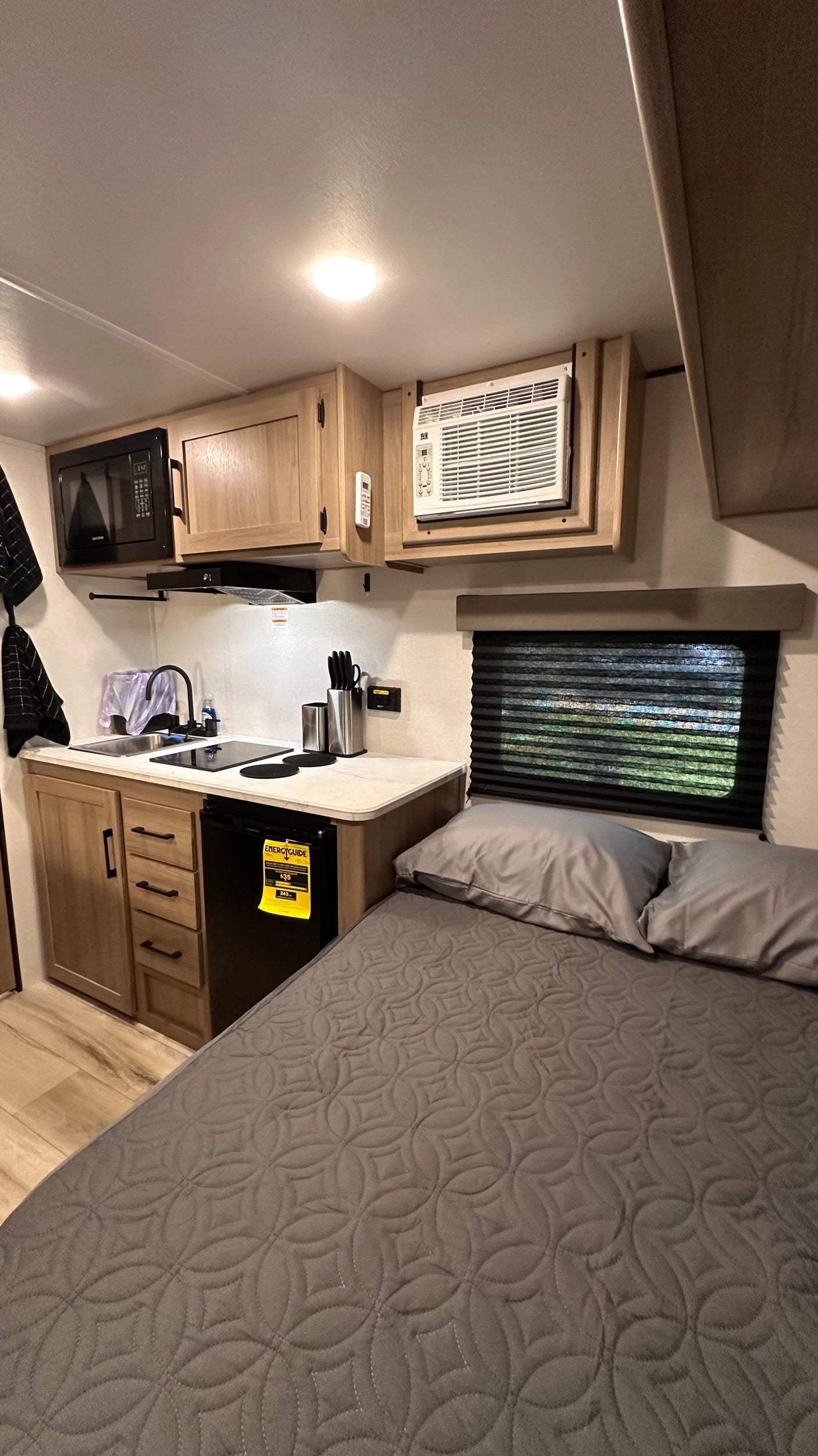 RV rental interior features a compact kitchen with microwave, sink, and fridge, plus a cozy bed for comfortable travel.