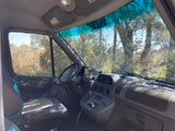 A spacious RV rental van cockpit. Features driver's seat, dashboard, & natural scenery visible through large windows.