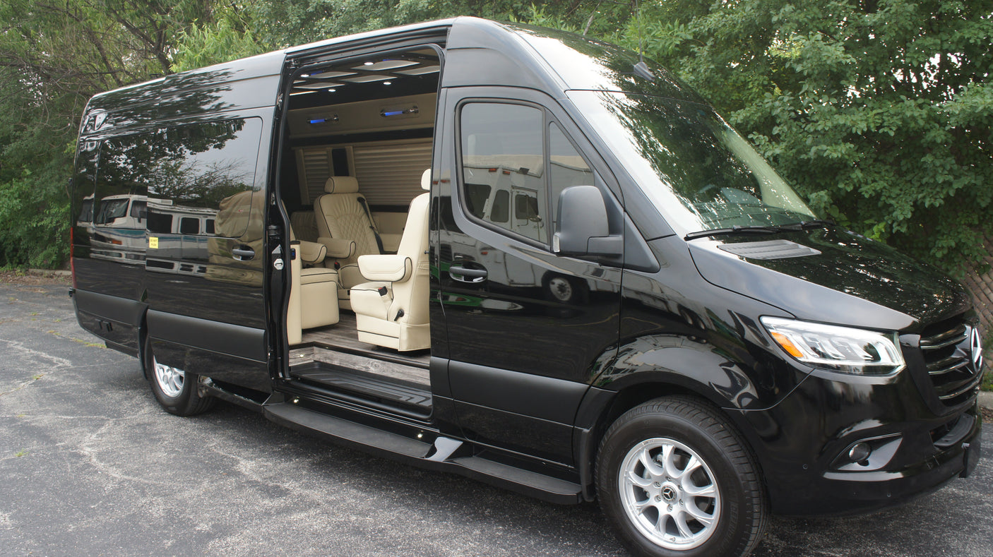 Black luxury Mercedes-Benz Sprinter van, perfect for rv rental, showcasing its custom cream interior through the open door.