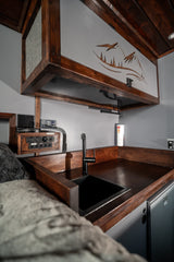 RV rental: custom interior with cozy kitchen, sink, charging ports, overhead storage, and bed area for adventure.
