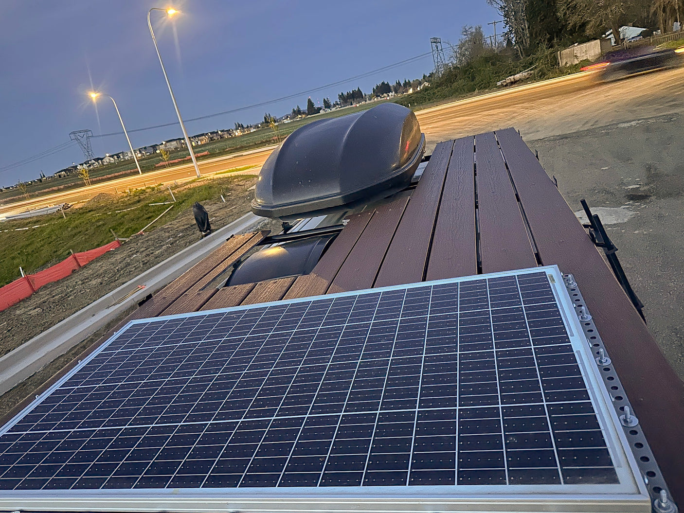 RV rental: rooftop with solar panel, slatted deck, and cargo box at dusk, ready for adventure.