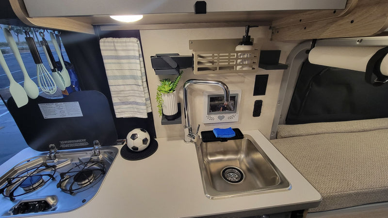 An RV rental kitchenette with a sink, two-burner stove, and useful accessories, perfect for road trip cooking. — photo 6