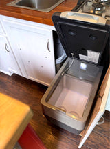 RV rental kitchen featuring a pull-out portable fridge, built-in sink, and stovetop for convenient cooking & storage.