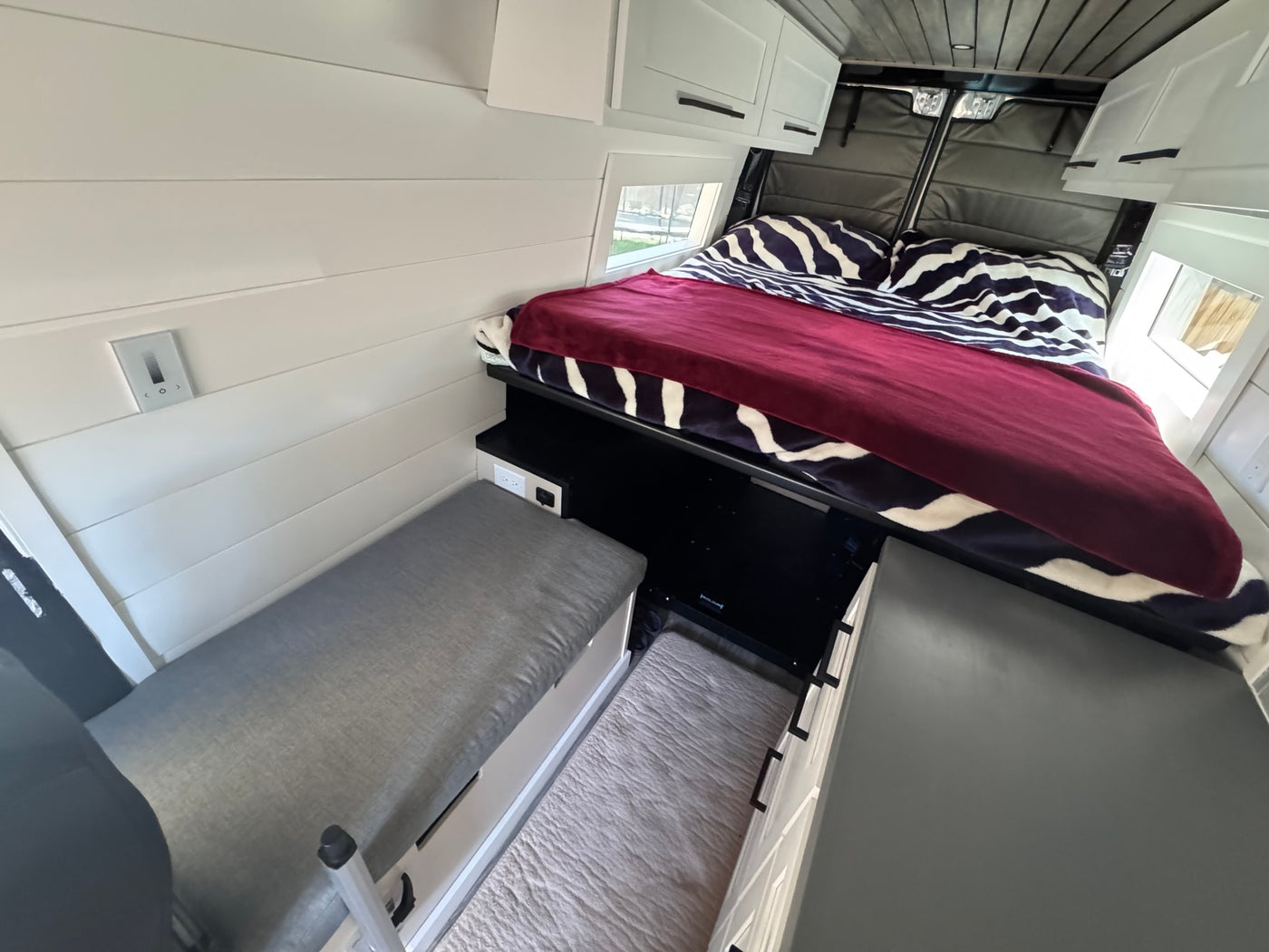  surrounded by vibrant green aspens and majestic snow-dusted mountains.|Your next adventure starts here! An Activan RV rental rests amidst majestic snow-capped mountains and a clear blue sky.|Light grey activan camper van with off-road tires & ladder — photo 14
