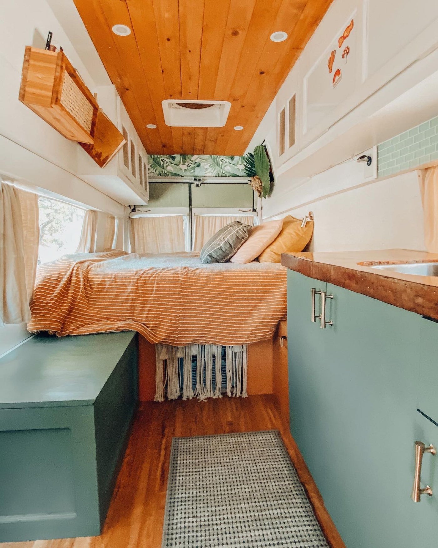 Stylish RV rental interior with cozy bed, green kitchenette, and warm wood accents. — photo 2