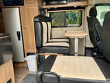 RV rental: Dinette with black & beige striped seating, table, fridge, microwave, & window view.