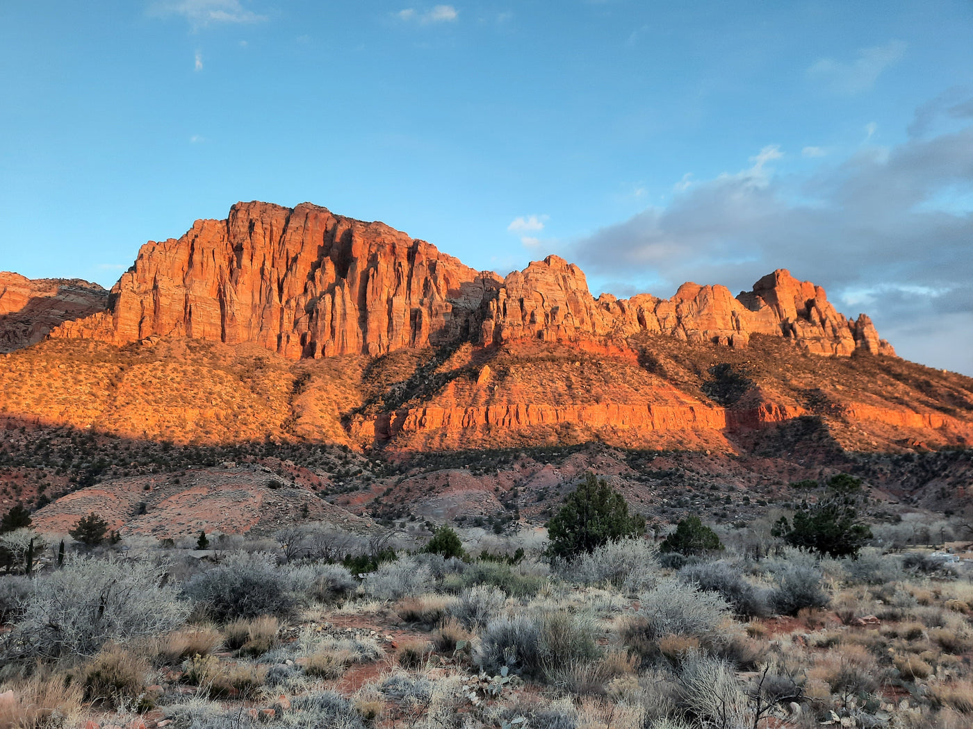 Sun-kissed red rock mountains rise above a vast desert landscape at sunset. Explore views like these with an RV rental adventure! — photo 19