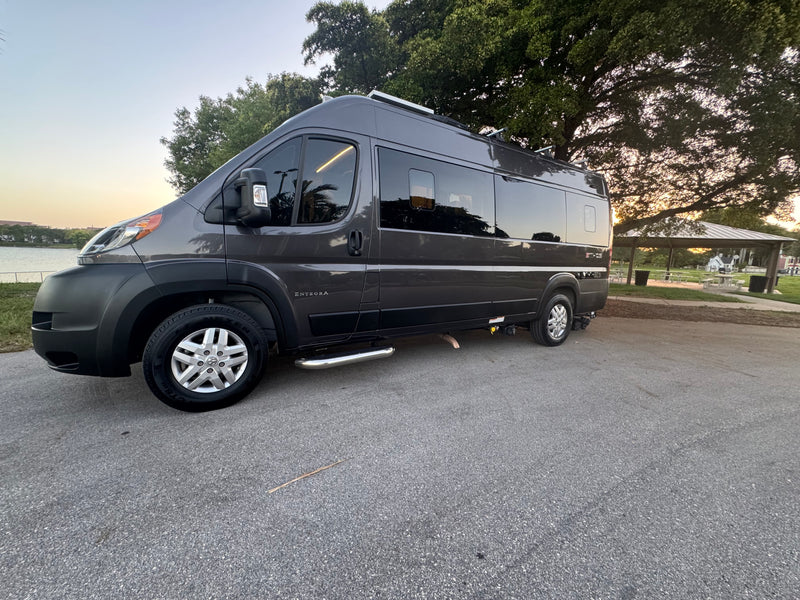 This sleek gray camper van, ideal for RV rental travel, is parked by a scenic lake with trees under a clear sky. — photo 11