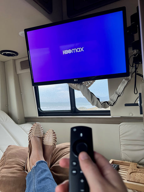 Relaxing in an RV rental: feet up, remote in hand for HBO Max. Enjoying the rainy ocean view.