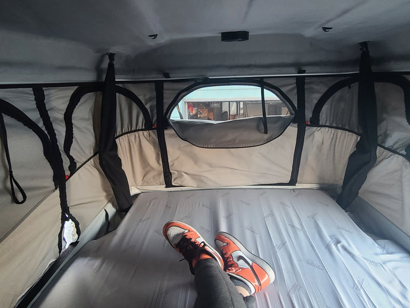 Relaxing inside an RV rental's pop-up tent. A person's feet in orange sneakers rest on the bed, with an outside view. — photo 4