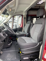 RV rental: Bright, clean van interior featuring front driver and passenger seats, steering wheel, and durable floor mat.