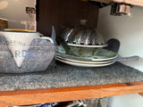 Compact kitchenware & felt liners in an RV rental cabinet, showing a mug, steamer, plates, and bowls for organized storage.