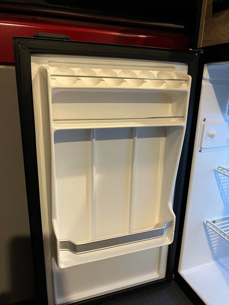RV rental: Bright, clean mini-fridge interior. Door features built-in storage for eggs and bottles, ready for your adventure.