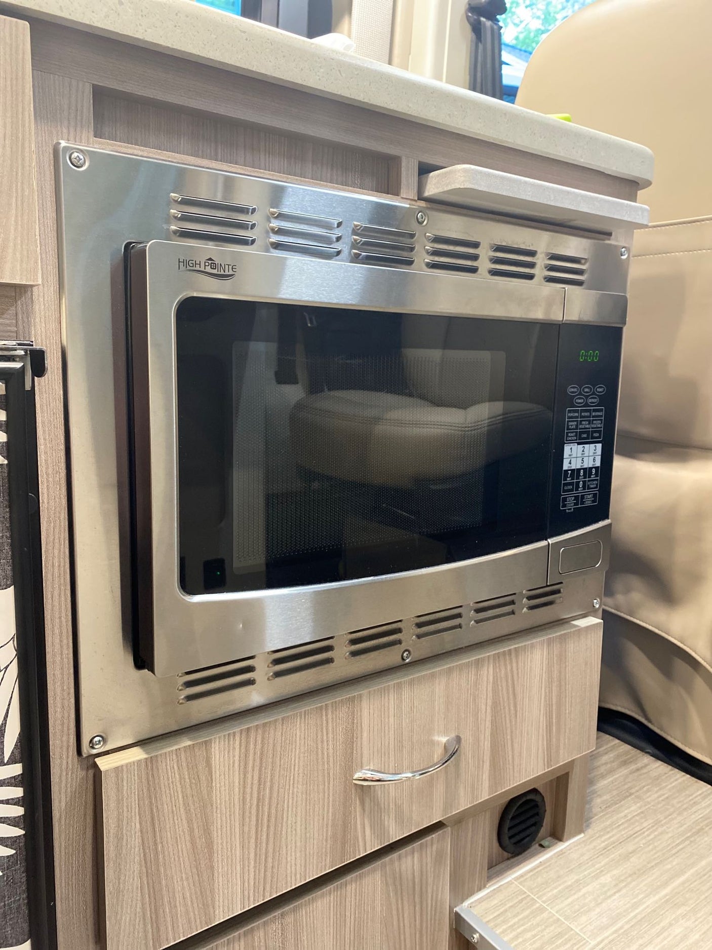 Built-in stainless steel microwave oven, ready for meals in this rv rental. Features digital display and control panel within a compact kitchenette.