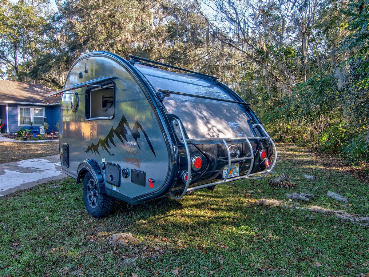  with an open window and side table set in a leafy campsite.|Experience adventure with this teardrop RV rental — photo 4