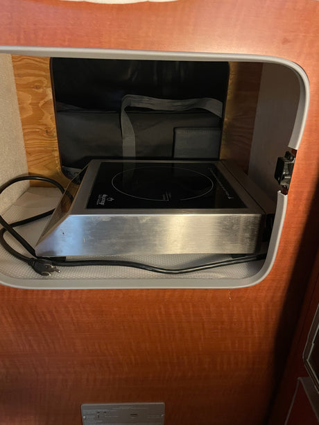 This RV rental features a compact duxtop induction cooktop, smartly stored in a cabinet for easy access.