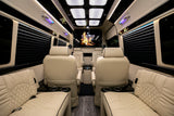 Luxury RV rental: plush cream quilted leather seating, ambient lighting, large entertainment screen, and wood floor.