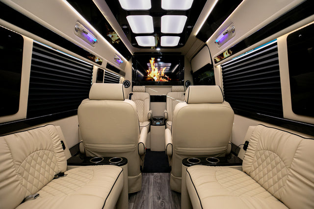 Luxury RV rental: plush cream quilted leather seating, ambient lighting, large entertainment screen, and wood floor.