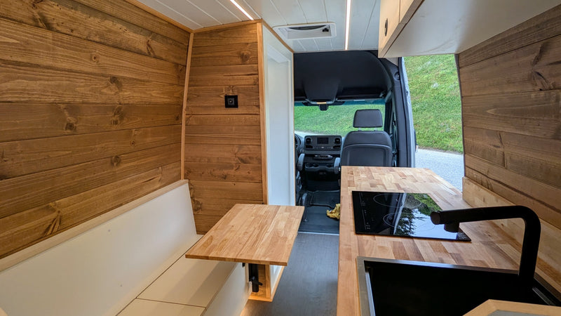  with its custom wood-paneled interior visible.|Step inside this RV rental! Features a compact kitchen with a fridge & wood counter — photo 8