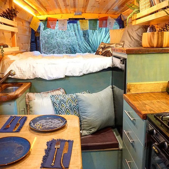  and dining table set for two. Perfect for your next adventure.|This cozy RV rental van interior features a wood-paneled kitchen — photo 4