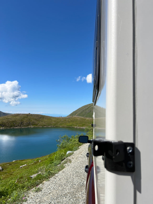  perfect for an rv rental adventure. Parked outdoors amidst bare trees.|Enjoying a serene lake and mountain view from a cozy RV rental on a sunny day. Perfect for your next scenic road trip!|Inside a modern rv rental: a comfy bed