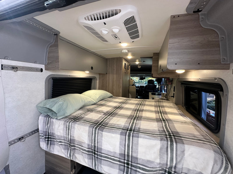  and plush bench seating. Green views outside.|This rv rental features a compact kitchen with a stove and sink — photo 9