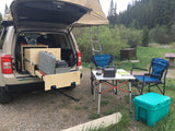 Overland RV rental setup: SUV with rooftop tent, pull-out kitchen, and full campsite furniture ready for adventure.