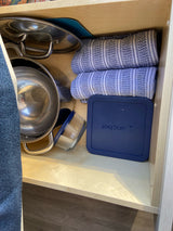 RV rental kitchen drawer showing organized pots, glass food storage with Anchor lid, and striped towels.