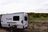 A white and grey GEO PRO travel trailer, available for rv rental, parked outdoors near a fence and trees.