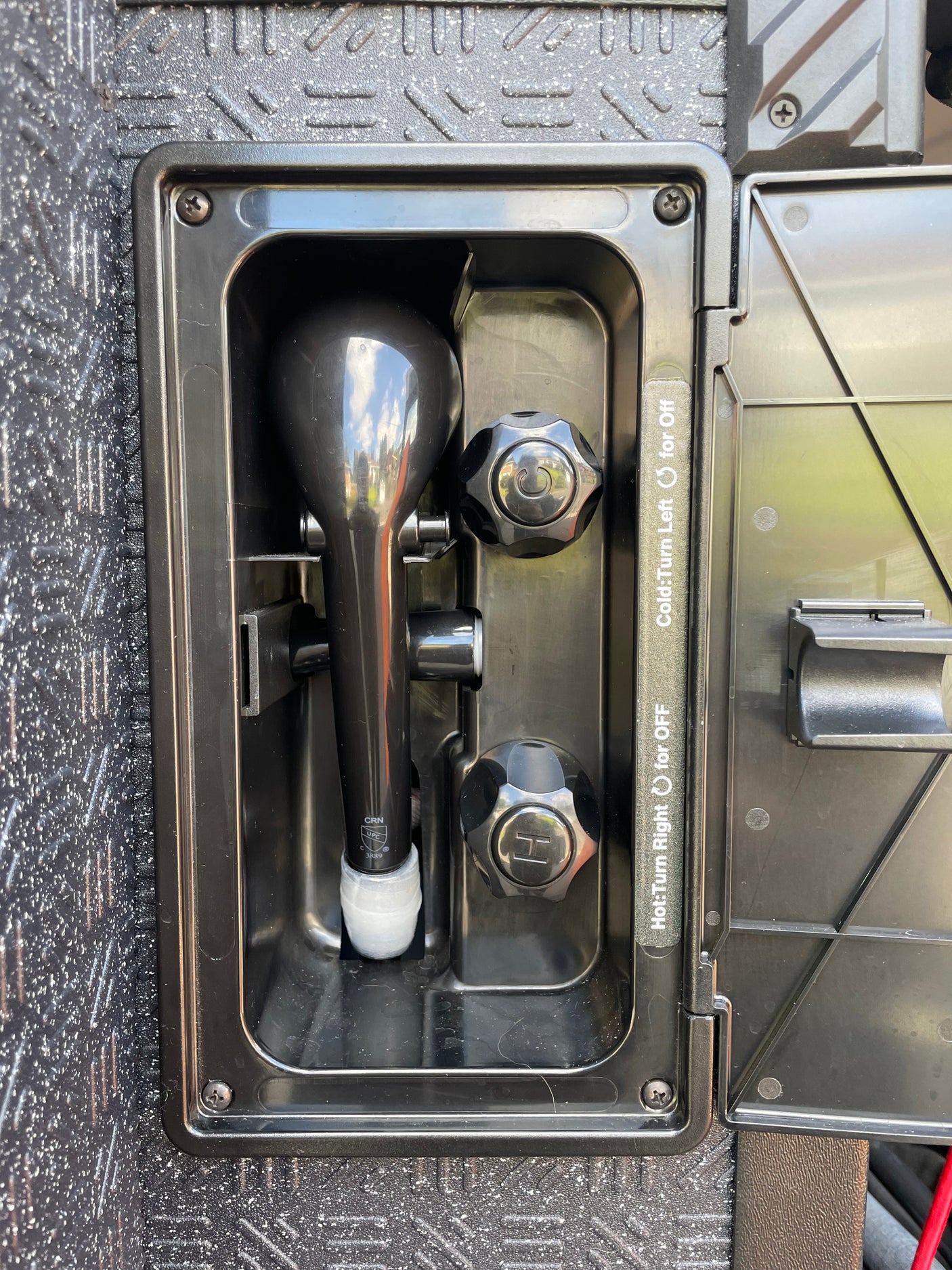 Outdoor RV rental shower unit with hot and cold water controls, ready for use.