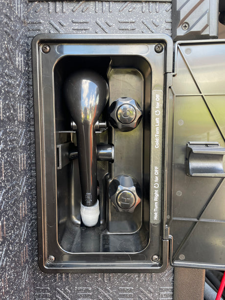 Outdoor RV rental shower unit with hot and cold water controls, ready for use.