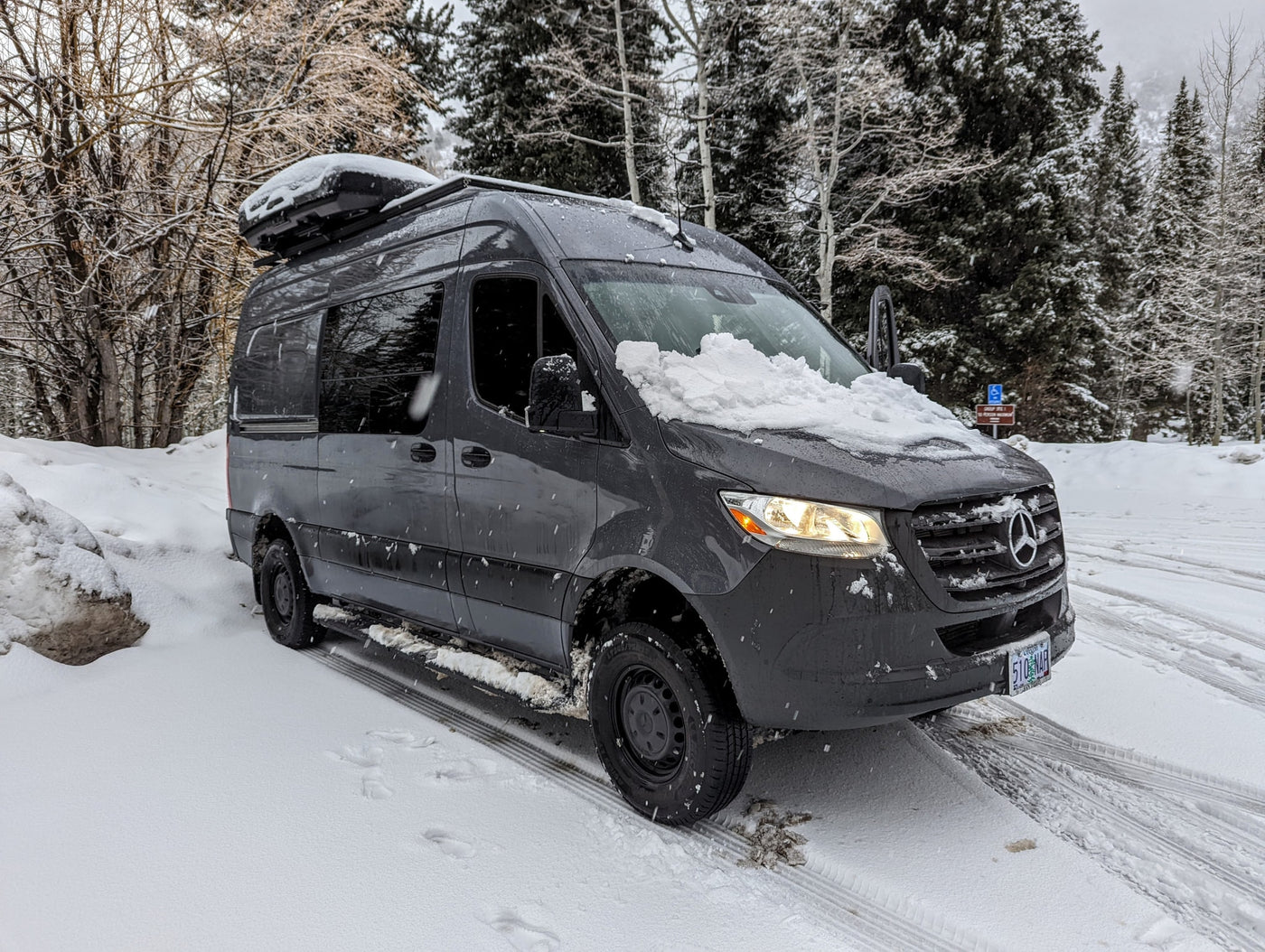  and overhead storage for group travel.|This black RV rental van is parked by a sandy beach — photo 6