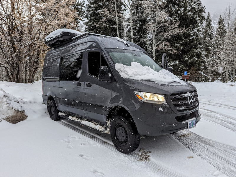  and overhead storage for group travel.|This black RV rental van is parked by a sandy beach — photo 6