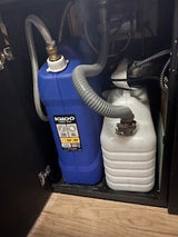 RV rental: Portable water tanks under counter. Blue Igloo and white jugs with hoses provide mobile water.