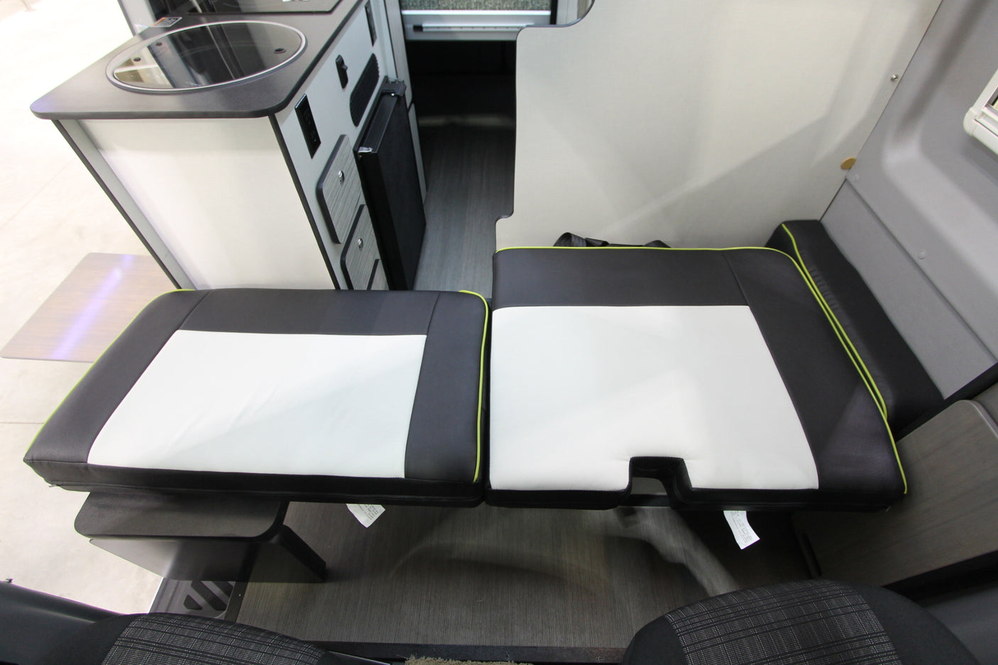 Inside this RV rental camper van: compact kitchen with sink/fridge, alongside adaptable black/white seating.