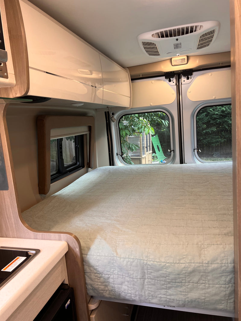 RV rental interior: A comfy bed, overhead storage, compact kitchen, and rear windows with backyard views. — photo 5