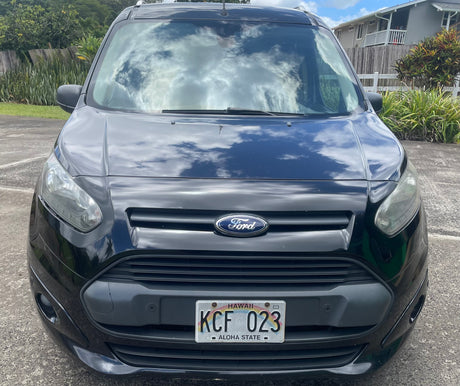 Front view of a black Ford van with Hawaii plate KCF 023. Ideal for a compact rv rental adventure, with clouds reflecting on the windshield.