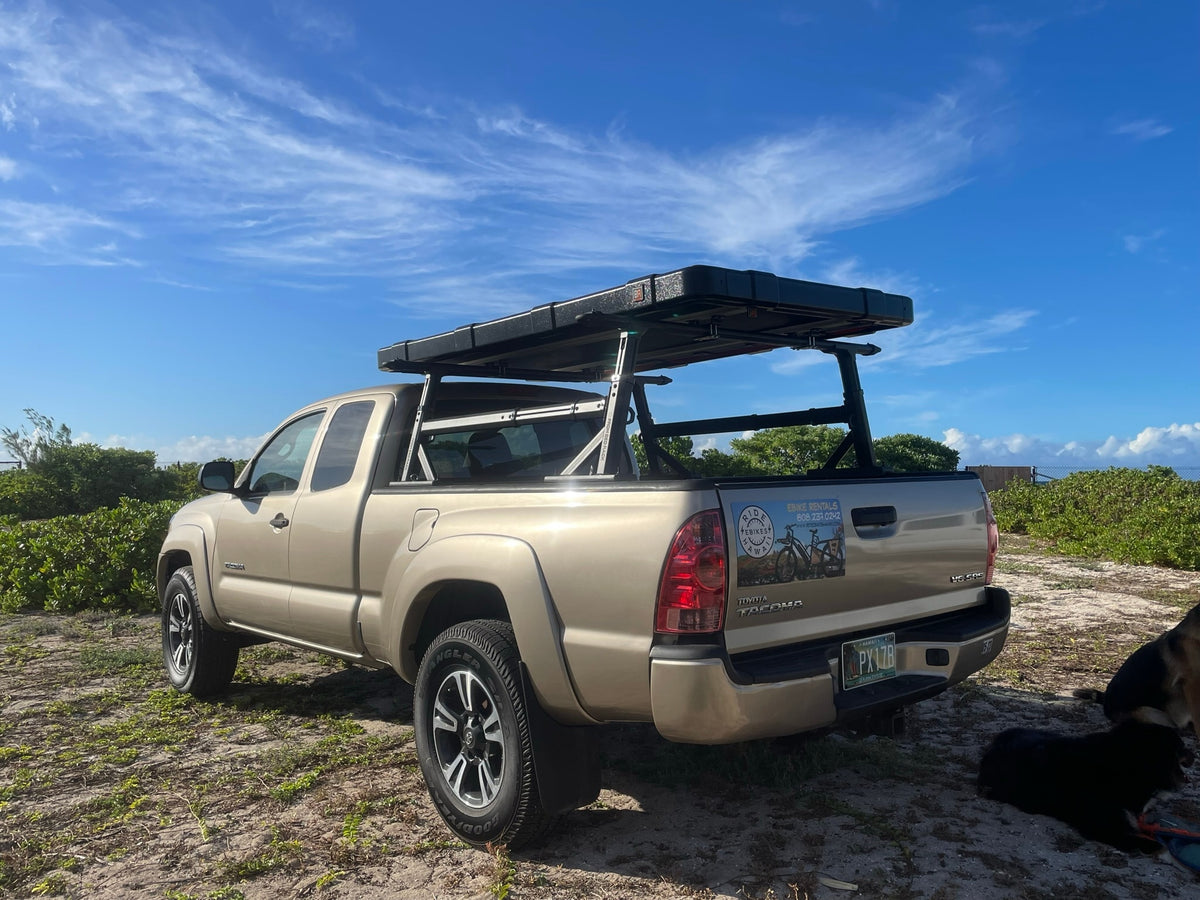 Tan Toyota Tacoma with rooftop tent, perfect for an RV rental beach adventure in Hawaii. Dogs relax nearby. — photo 2