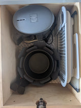 Compact kitchen storage in an RV rental drawer: multi-cooker, foldable dish rack, fan, & pot holders on a patterned mat.
