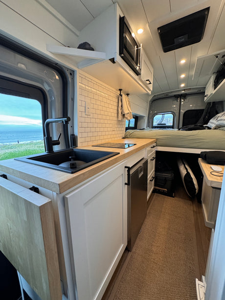 This RV rental boasts a modern kitchen, comfy bed, & ocean views. Compact, bright interior perfect for van life adventures.