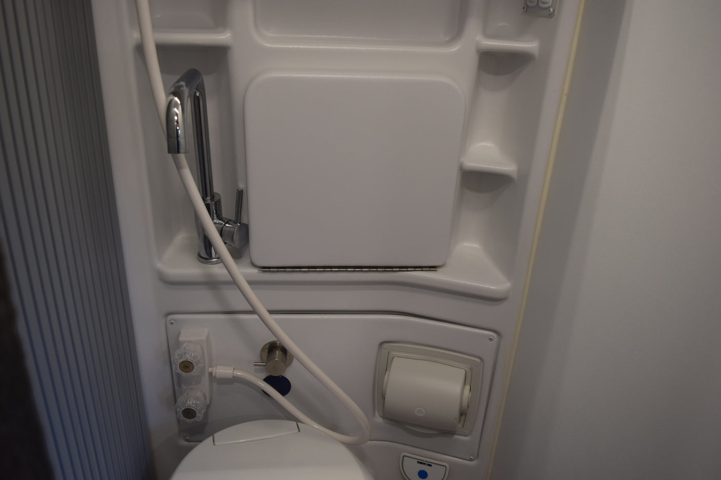 Compact RV rental wet bath with toilet, shower, and fold-down sink for efficient space.