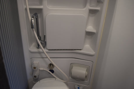 Compact RV rental wet bath with toilet, shower, and fold-down sink for efficient space.