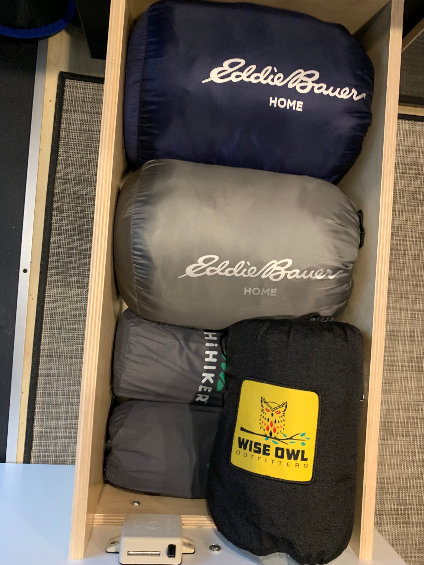 Optimized **RV rental** storage: Packed Eddie Bauer, HiHiker, and Wise Owl Outfitters outdoor gear in a wood drawer.