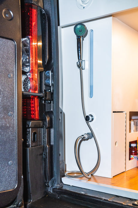 RV rental: Tailgate view revealing a convenient outdoor shower system built into the van's custom interior.