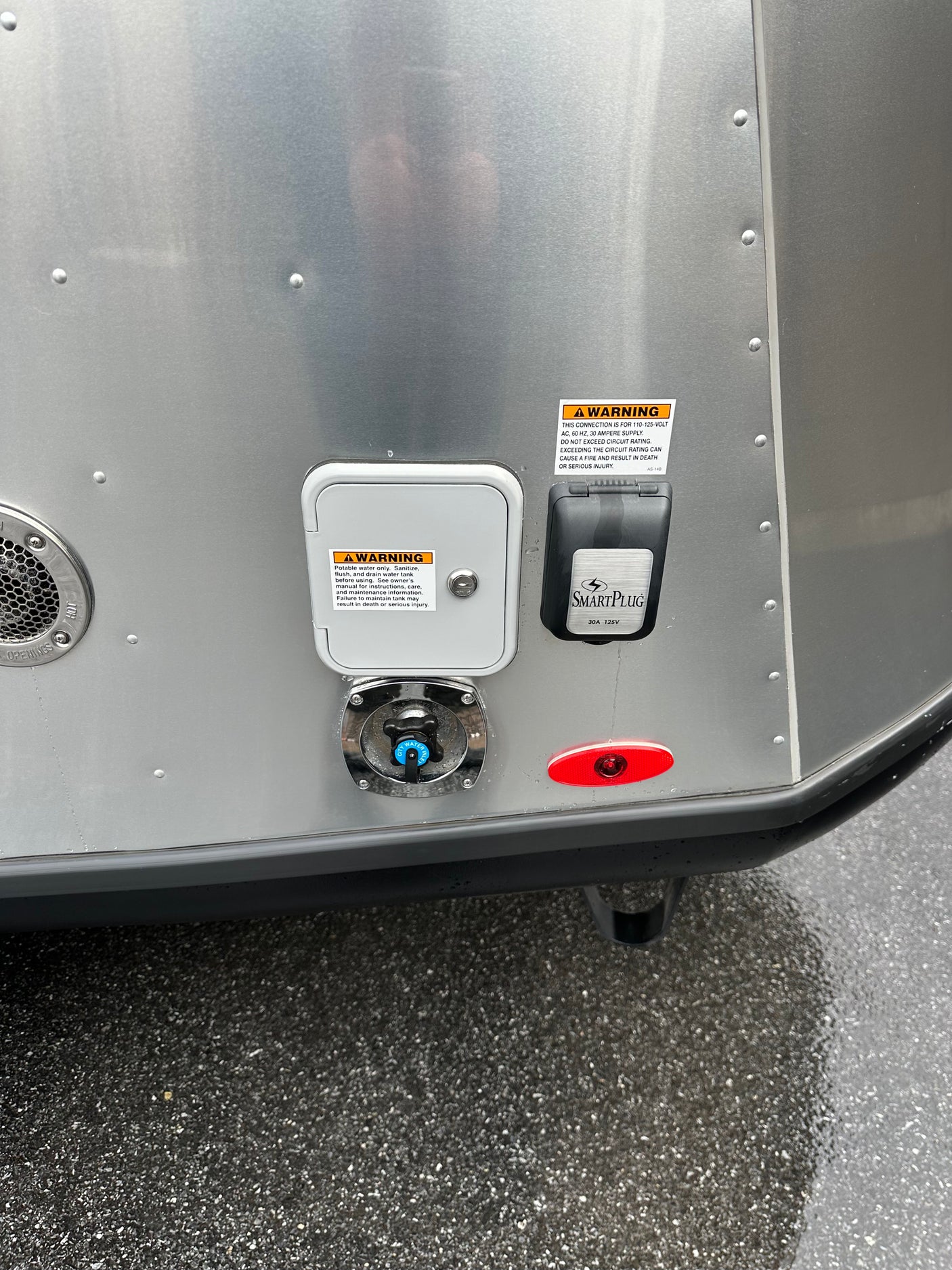 RV rental exterior showing water and SmartPlug electrical inlets, plus a hot water vent. Safety warnings are prominent.