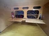 RV rental bedroom view: compact space with overhead storage, blankets, fire extinguisher, and fold-down side tables.