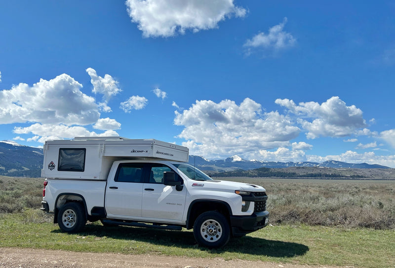 White Chevy truck with a pop-top truck camper, perfect for RV rental trips to scenic mountains under blue skies. — photo 4