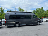 Full side view of a dark gray Mercedes-Benz Sprinter RV van, appearing as an rv rental, parked in a lot.