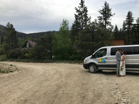 Bride & groom by their WANDERVANS **RV rental** van on a scenic mountain road. Perfect for an adventurous wedding!