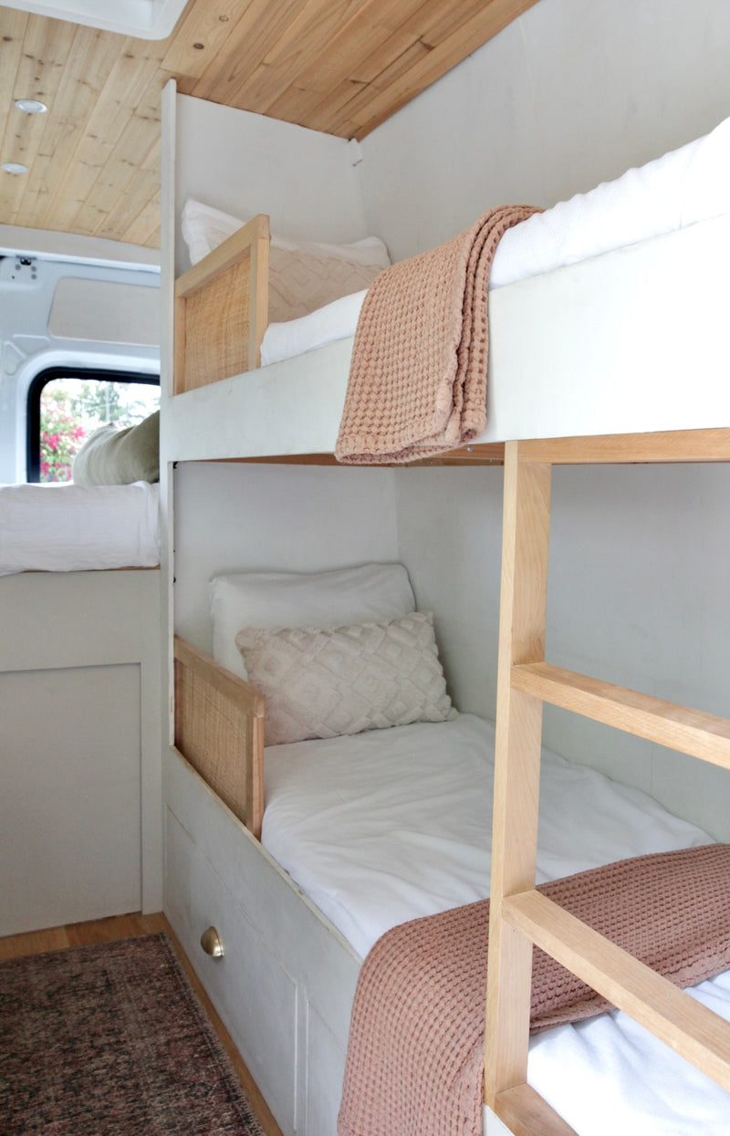 Experience comfort in this RV rental! Custom light wood & rattan bunk beds with soft white bedding, creating a cozy sleeping space. — photo 3
